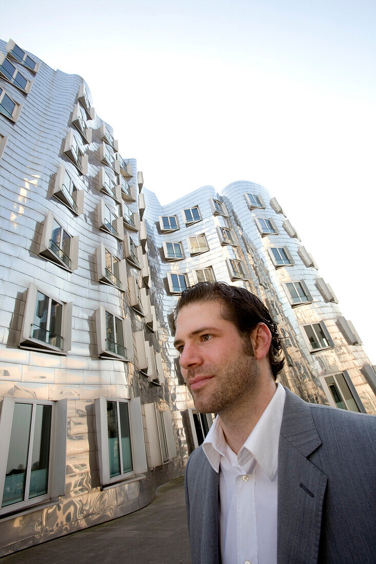 young buisness man in front of modern architecture, district of media, new district of Düsseldorf, harbor, state capital of NRW, North-Rhine-Westphalia, Germany