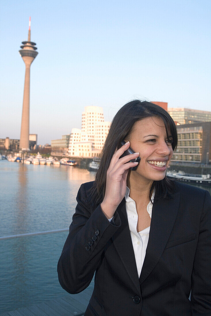 junge Geschäftsfrau telefoniert im Medienhafen von Düsseldorf, Landeshauptstadt von NRW, Fernsehturm, Rheinturm, neuer Zollhof, Deutschland