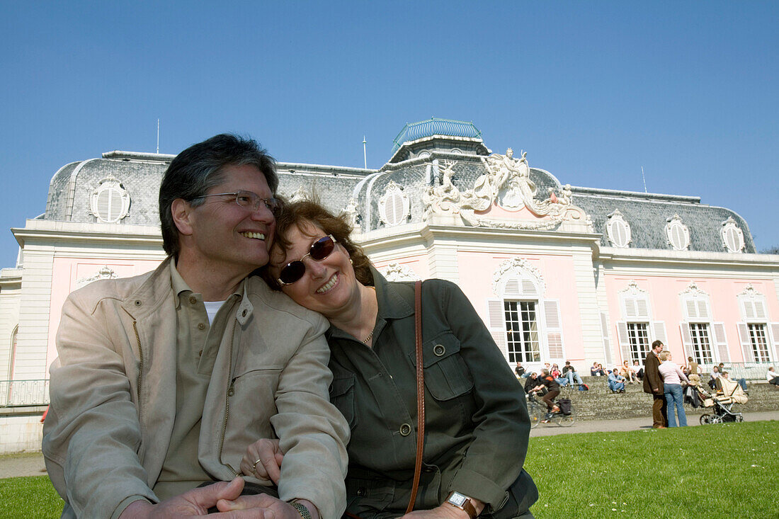 Mature adult couple sitting in front of the Benrath castle, Düsseldorf, state capital of NRW, North-Rhine-Westphalia, Germany