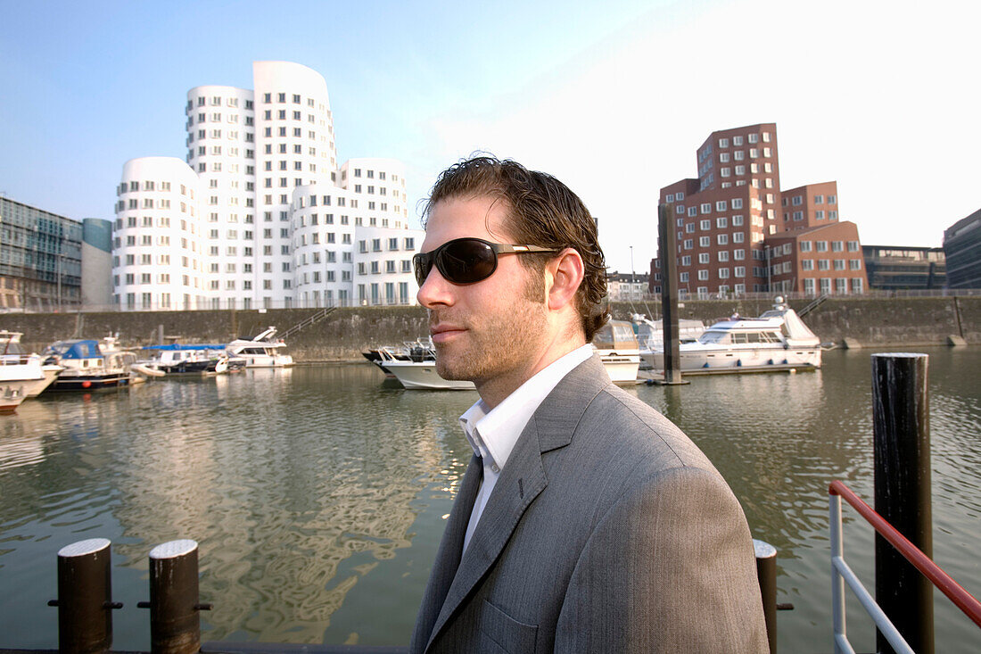 Junger Mann mit Sonnenbrille, neuer Zollhof, Architektur von Frank O.Gehry, Medienhafen in Düsseldorf, Nordrhein-Westfalen, Landeshauptstadt in NRW, Deutschland