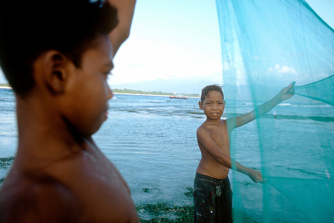 Young fishermen from Gili Trawangan practising with fishing net, Lombok, Indonesia
