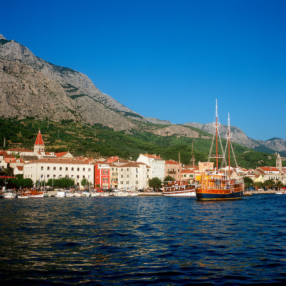 makarska, dalmatia, croatia, adriatic sea, vacation, travel, tourism, tourists, town right on the waterfront, water, boats, sightseeing, range of mountain in the back, view from the waterside, golden light