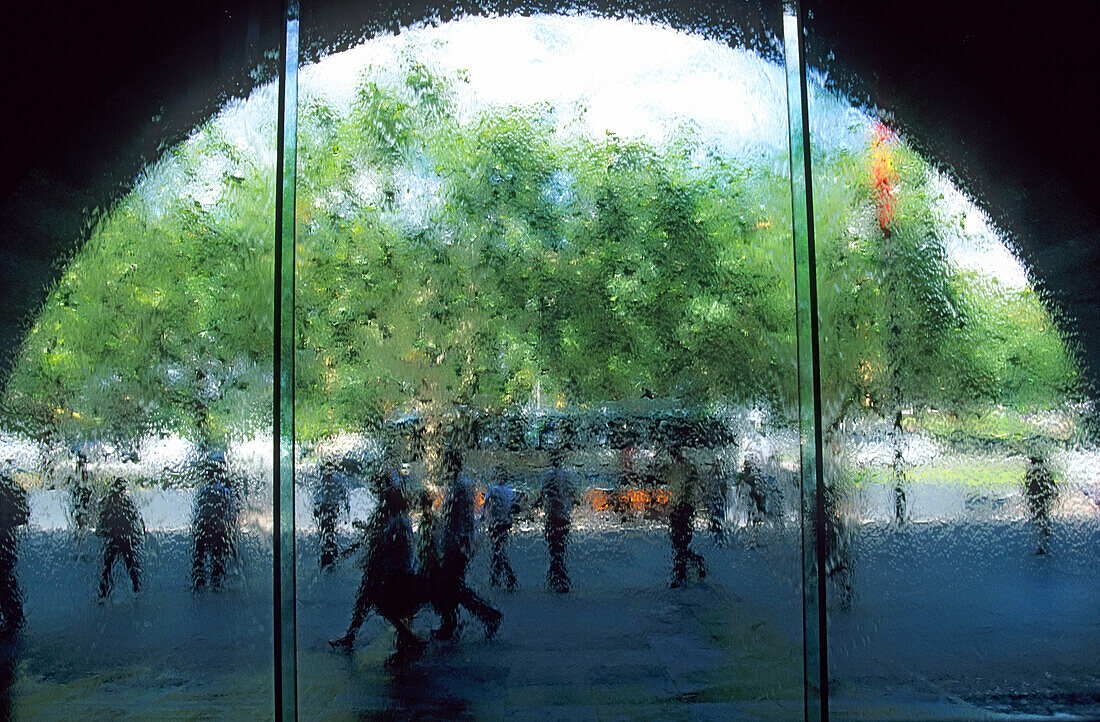 Blick durch die Eingangstür in der Nationalgalerie in Melbourne. Über die Glasscheibe läuft Wasser.
