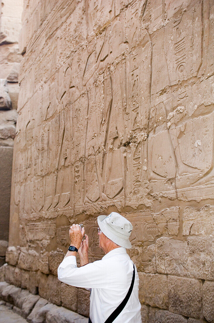 A tourist taking a photo of Hieroglyphics, Karnak Temple, Luxor, Egypt