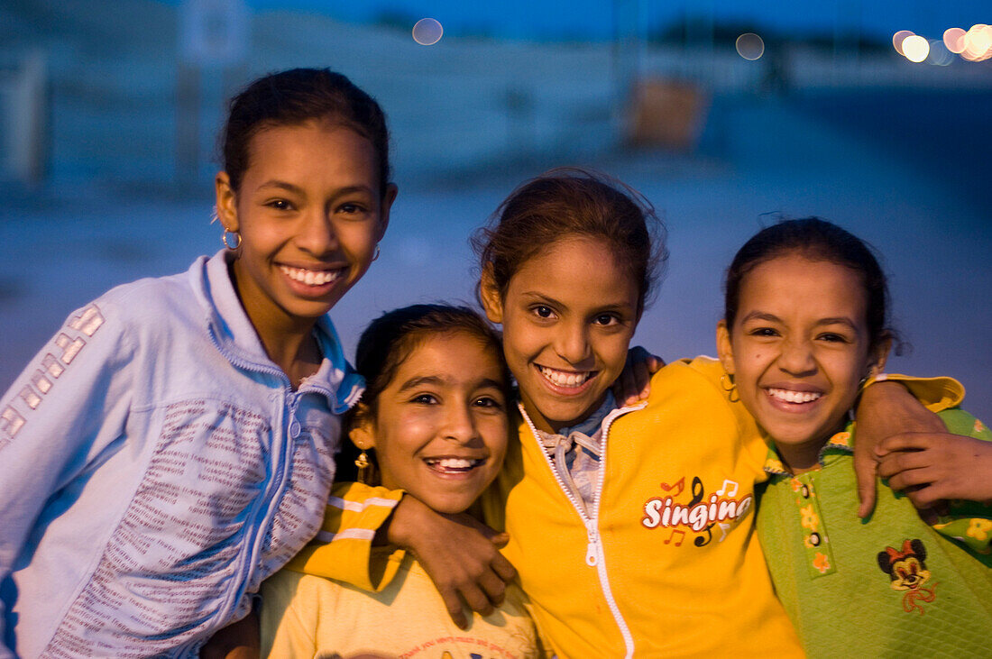 Four girls, friends, standing with arms around each other, dusk, Luxor, Egypt