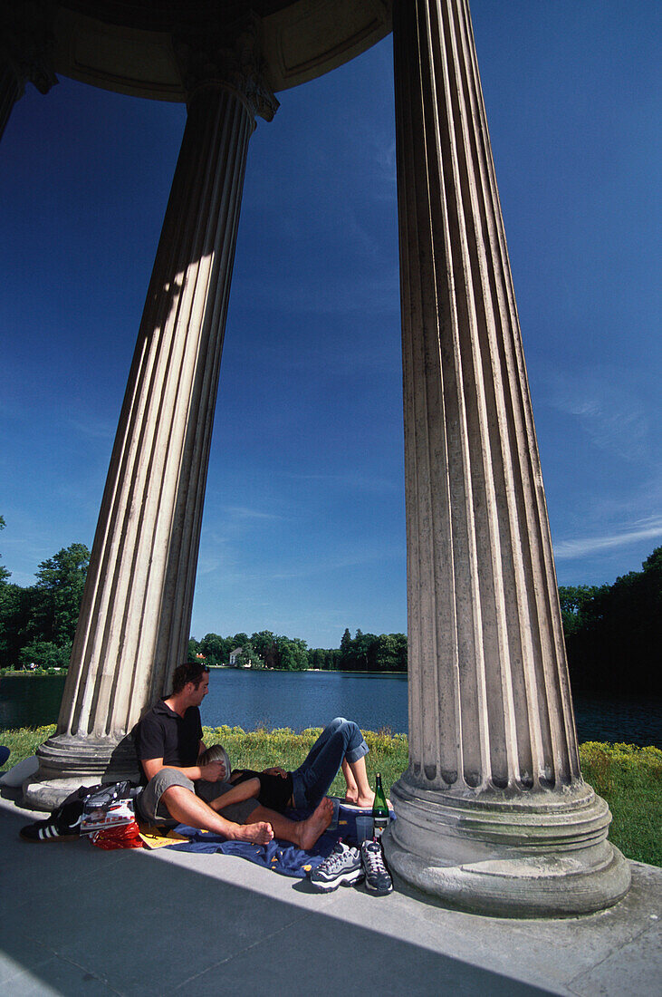 Couple having a rest at the Apollo Temple, Nymphenburg, Munich, Bavaria, Germany