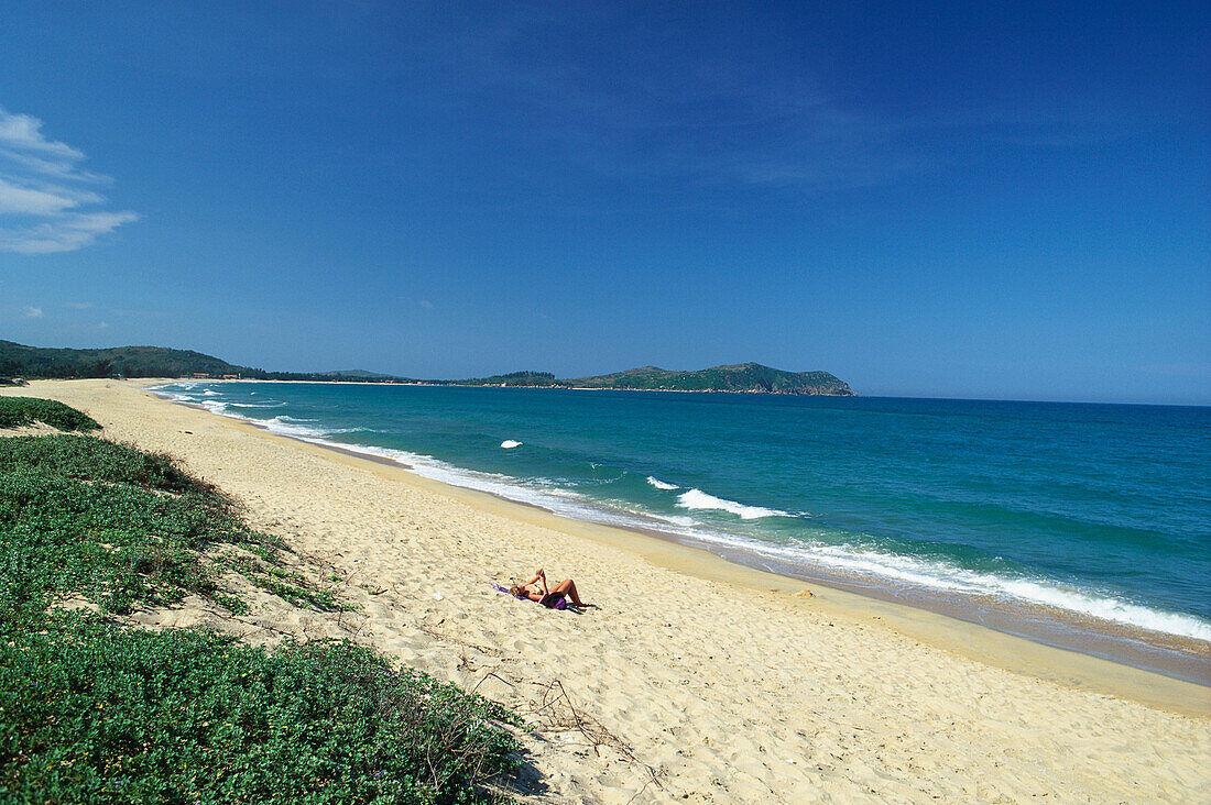Woman sunbathing on a sandy beach near Na Thrang, Vietnam