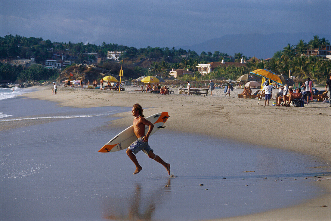 A surfer running into the water, Playa Zicatela, Puerto Escondido, Oaxaca, Mexico, America