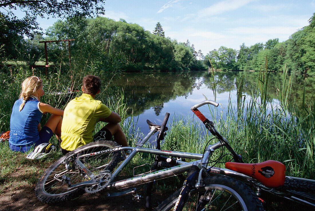 Two people, mountainbiking, having a rest at a lake, Fünfseenland, Five Lakes, bavaria, Germany