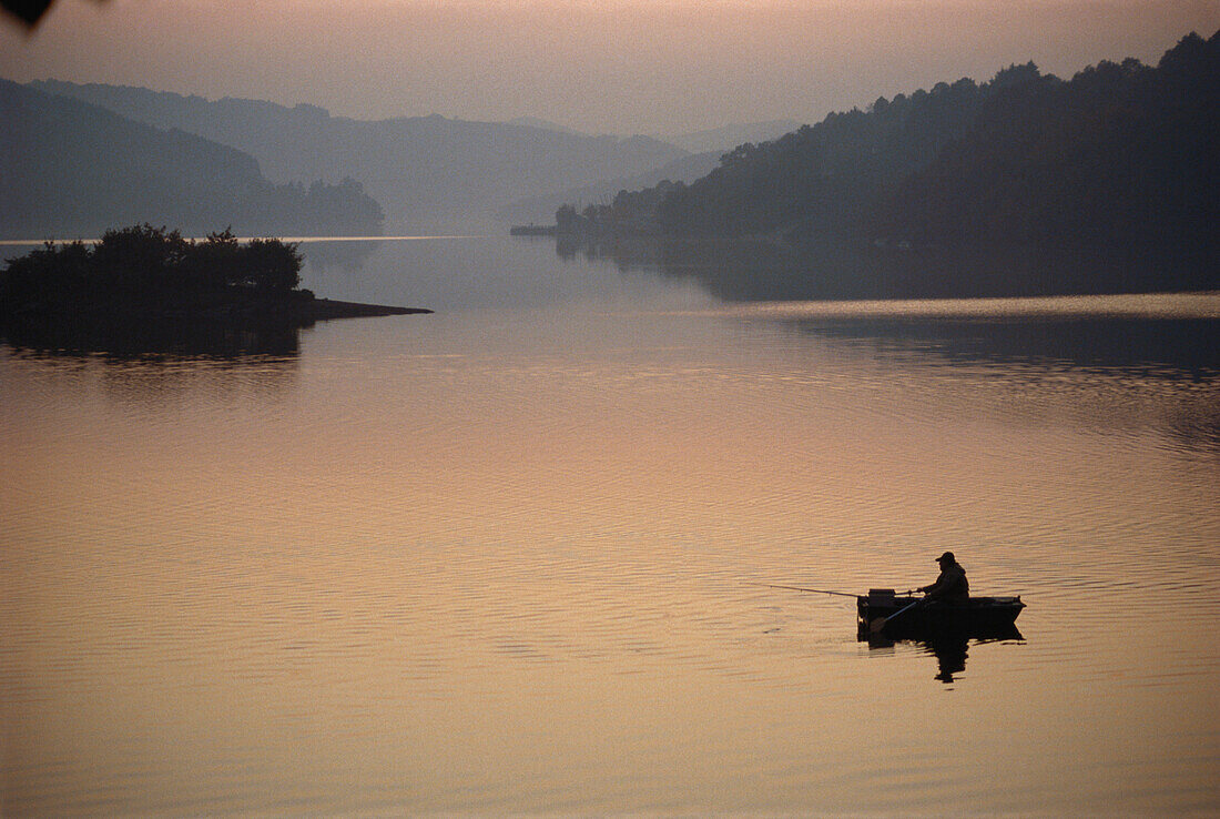 Fisherman in a boat on Sauer Reservoir, Luxembourg