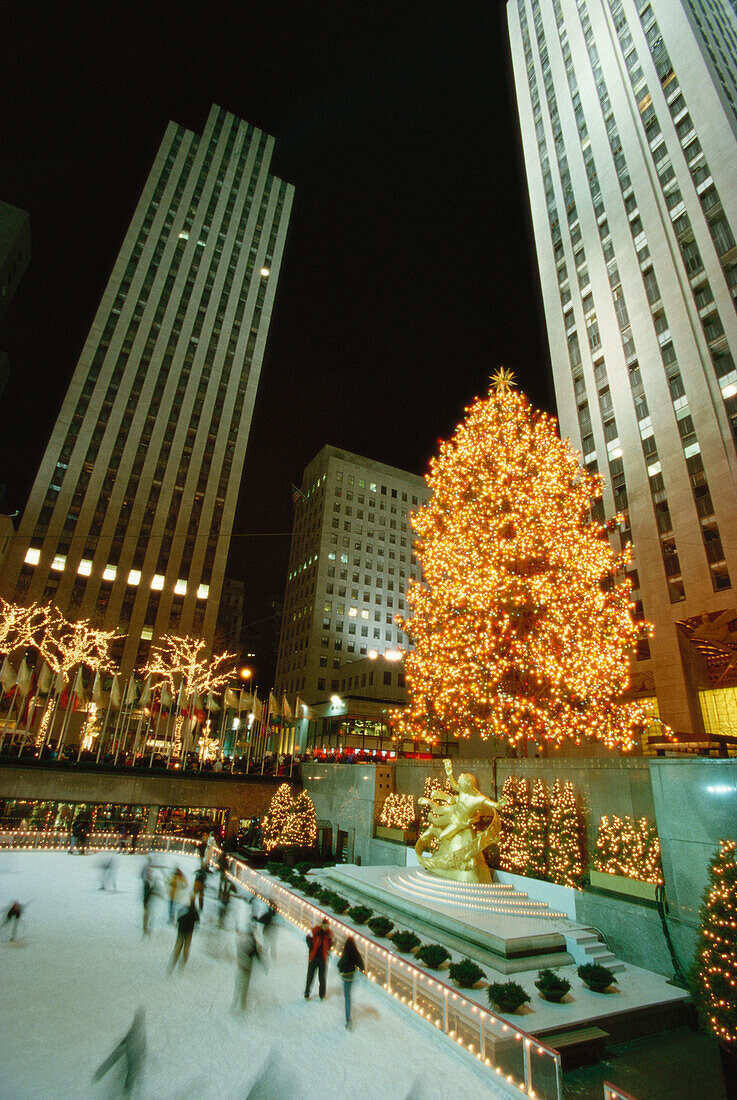 Rockefeller Center at night with Christmas decorations, People ice scating in the foreground, New York City, USA