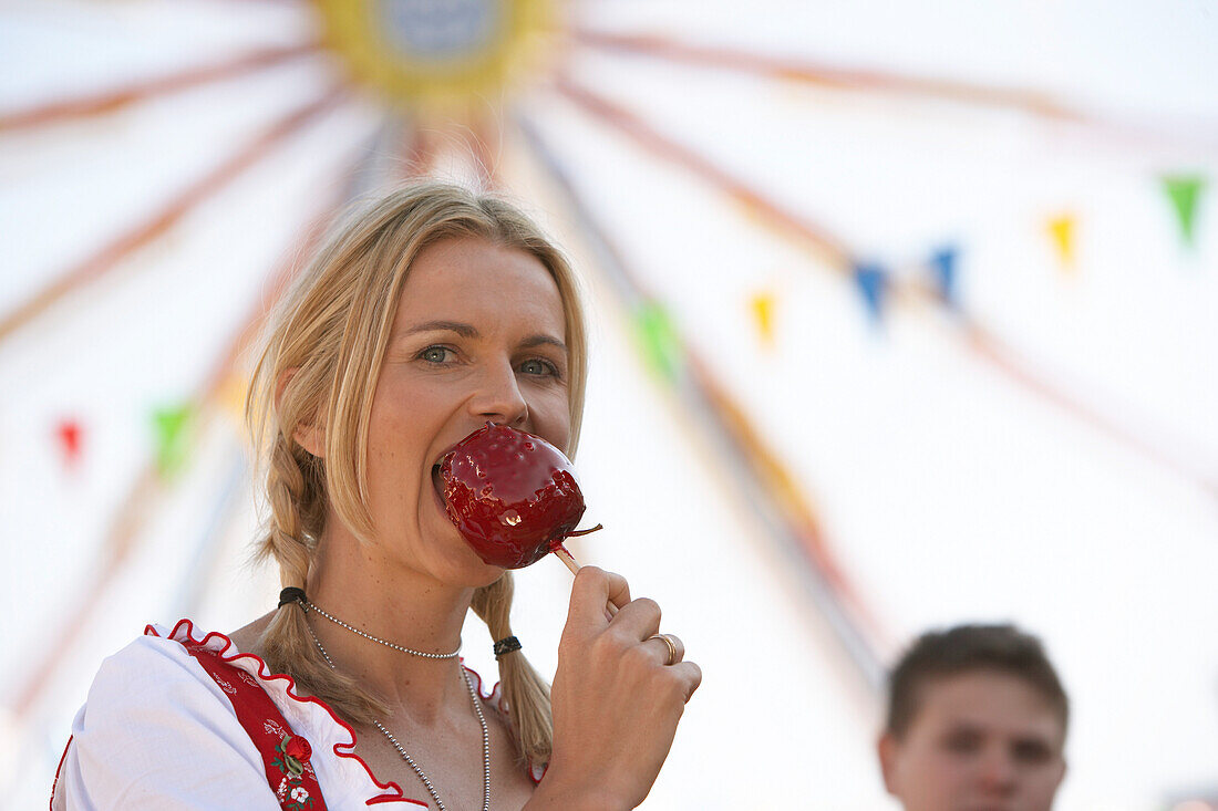 Woman wearing dirndl dress eating candied apple