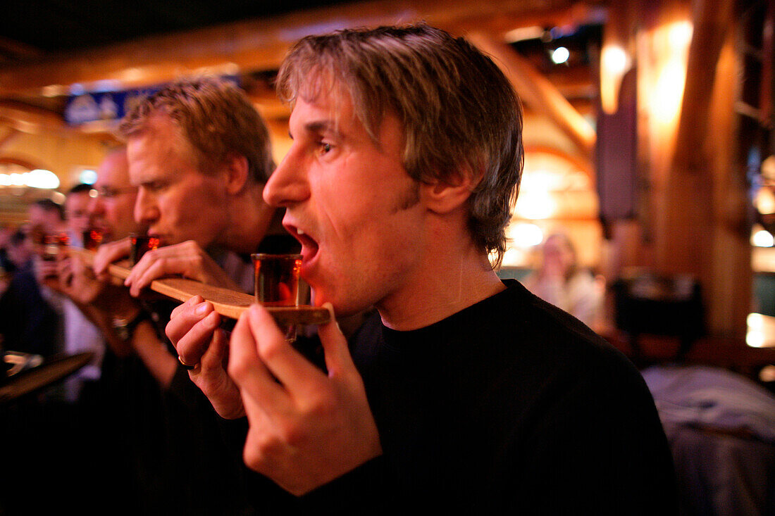 Eine Gruppe von Männer trinken Schnapps von einem Ski, Shot Ski, Caribou Lodge, Banff, Alberta, Kanada