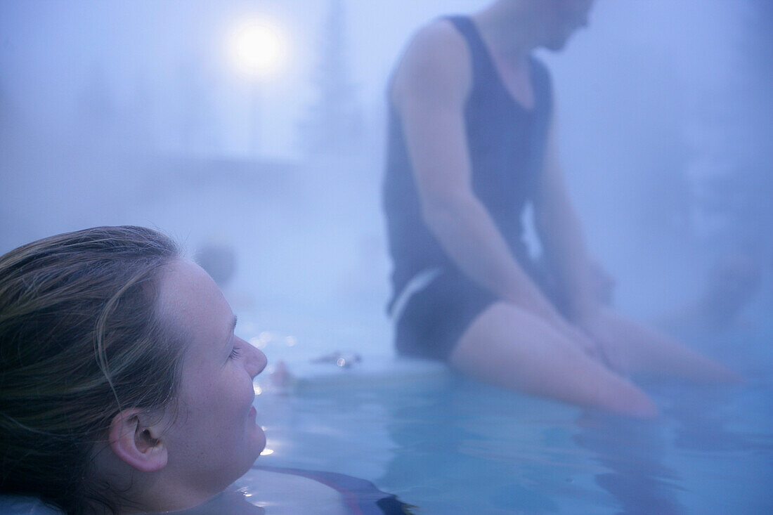 Young couple sitting in hot spring, Bavaria, Germany