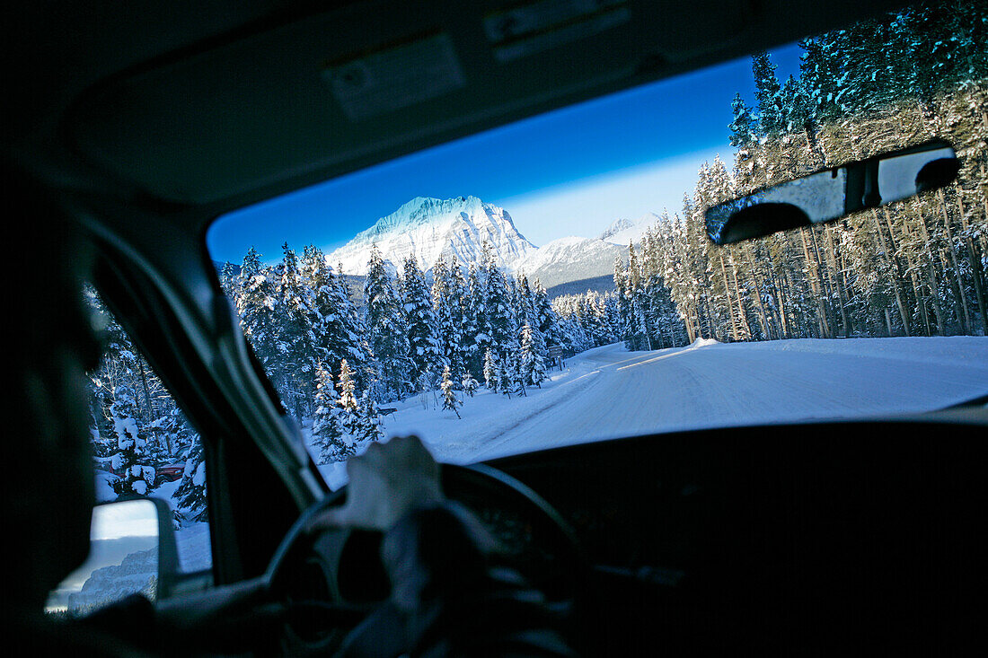 View through car windscreen towards snowy highway, near lake louise, Alberta, Canada