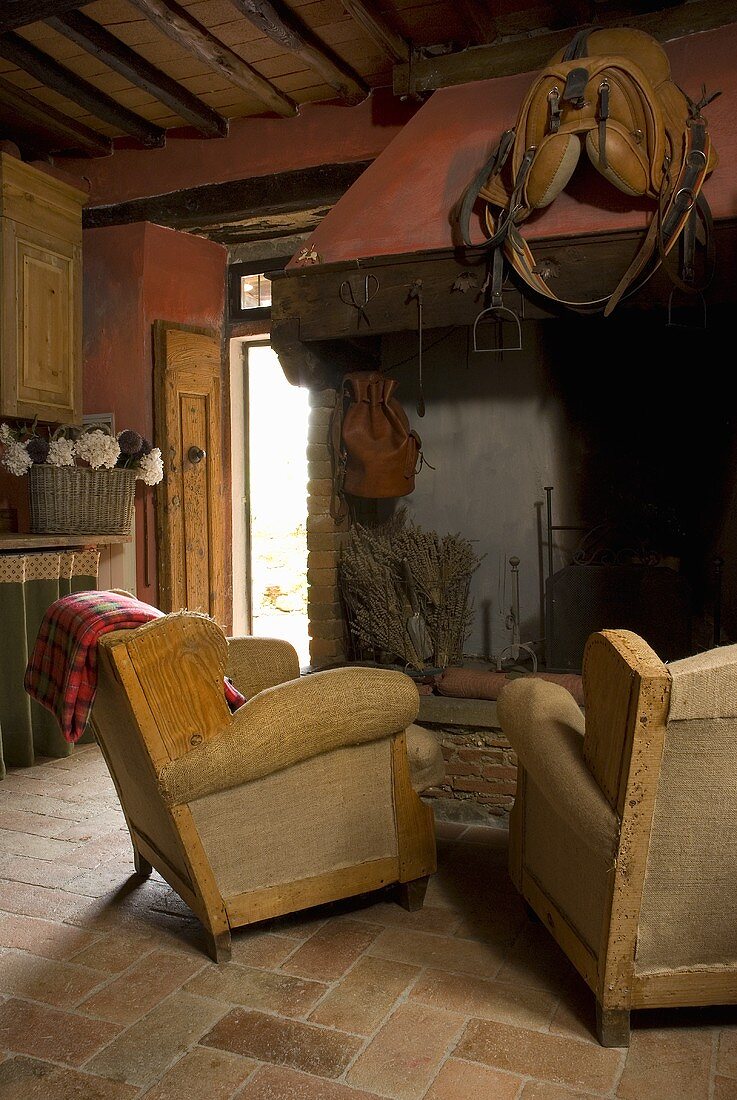Wing chairs in front of a fireplace on terracotta floor in a country cottage
