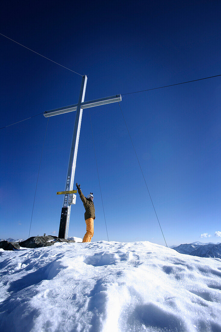 Cheering skier near summit cross, Grawand peak, Schnals Valley, Oetztal Alps, South Tyrol, Italy, MR
