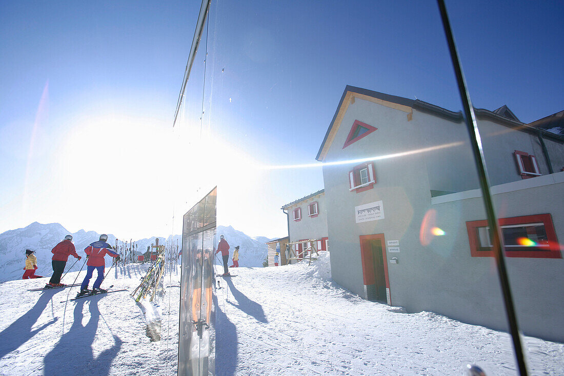 Skifahrer und Skihütte Bella Vista spiegeln sich in einer Fassade, Schnalstal, Südtirol, Italien