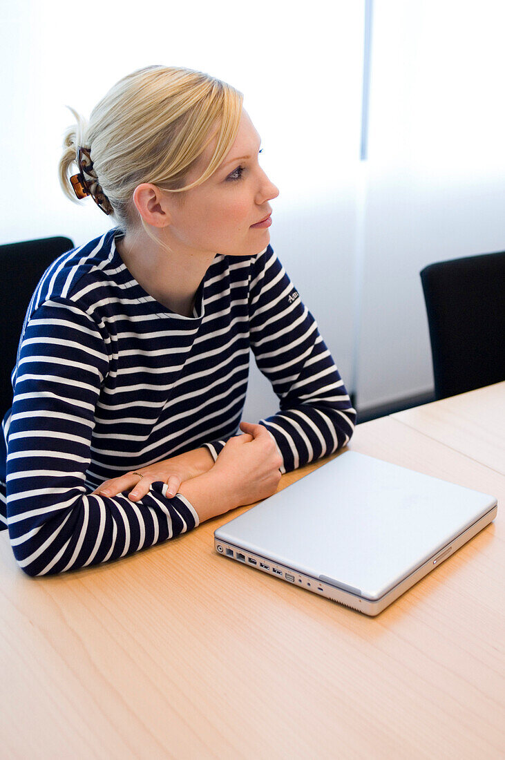 Yunge Frau sitzt an Konferenztisch mit Laptop, Luxemburg