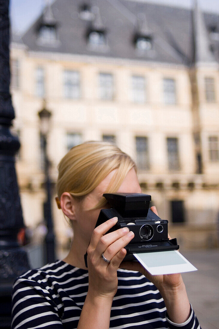 Woman taking picture with instant camera, Luxembourg