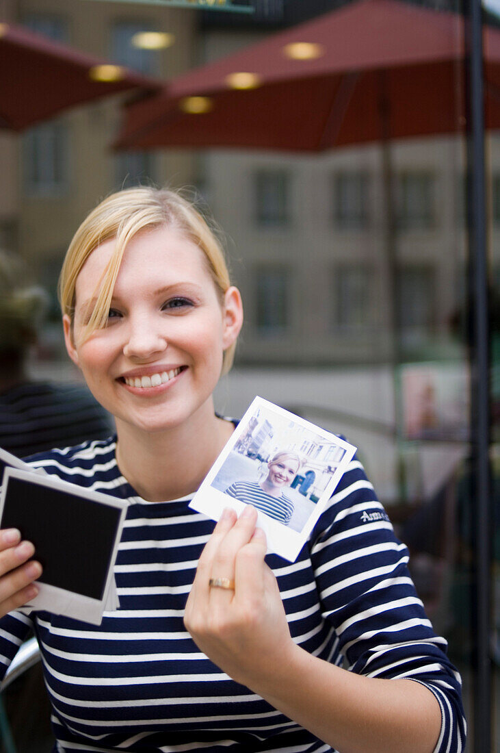 Young woman sitting in a pavement cafe und looking at photos, Luxembourg