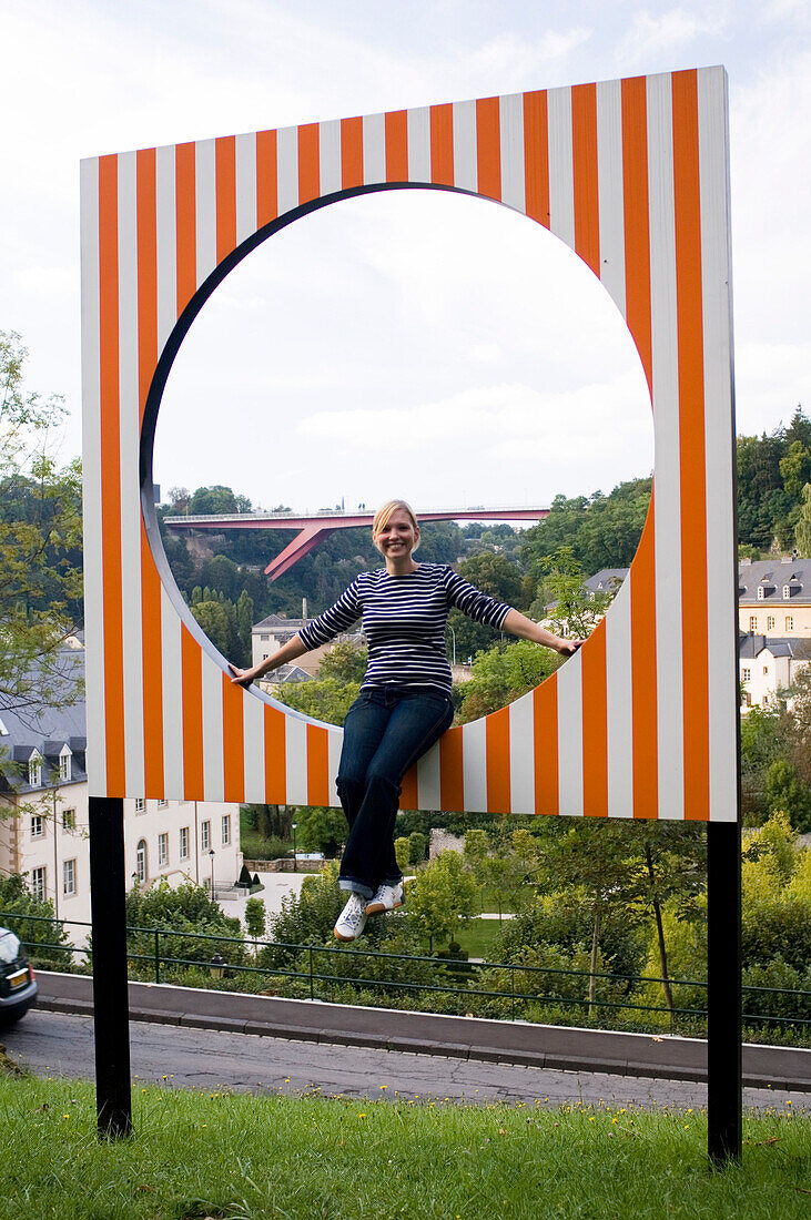 Frau sitzt auf einem Kunstwerk, Luxemburg