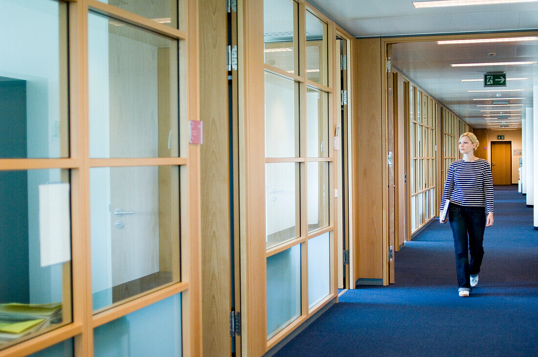 Young woman walking over corridor inside an office building, Luxembourg