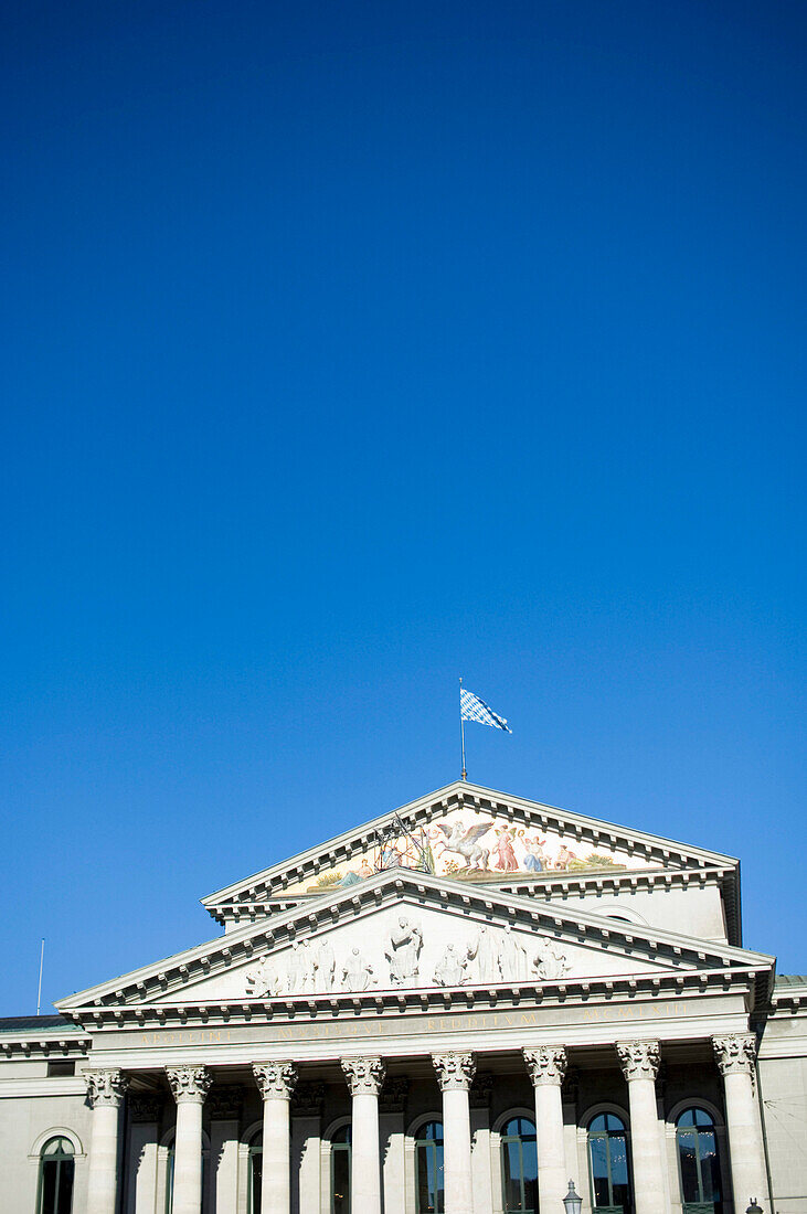 Historical building with flag on top under a blue sky, Munich, Bavaria, Germany