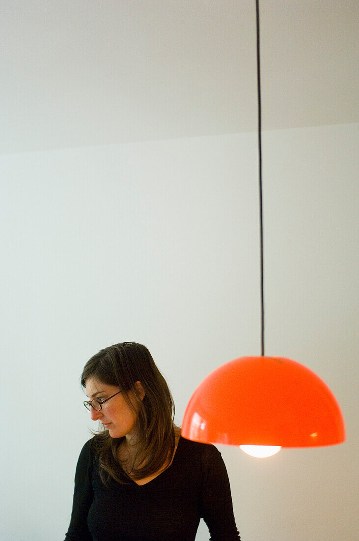 Young woman wearing spectacles looking down, lamp in foreground, Munich, Bavaria, Germany