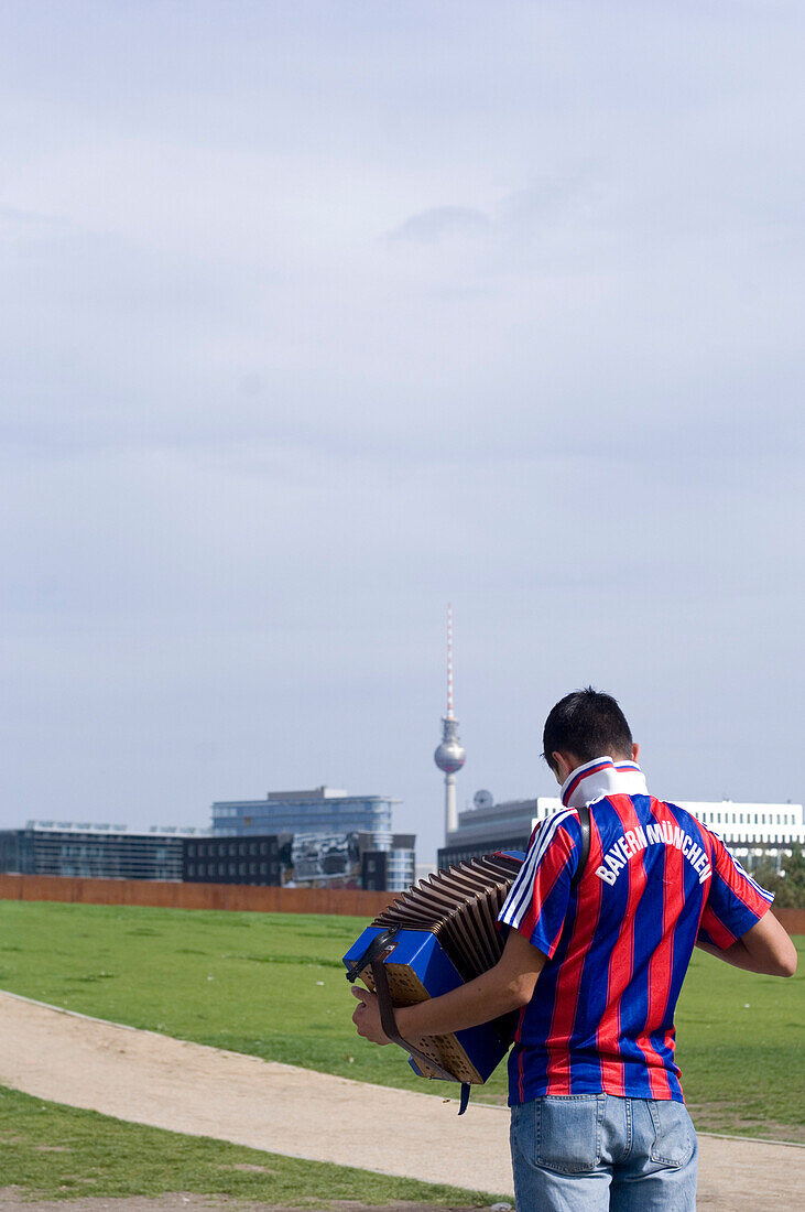 Junger Mann im Fussballtrikot spielt Akkordeon, Berlin, Deutschland