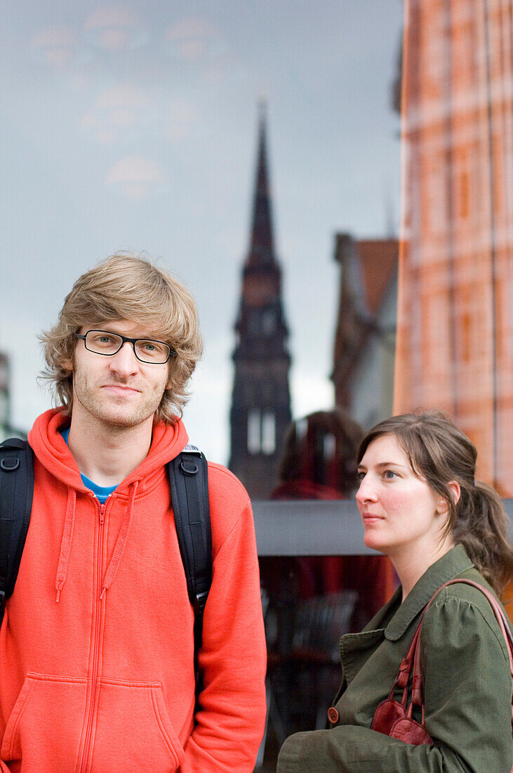 Junges Paar vor einer Glasscheibe, Mann blickt in die Kamera, Hamburg, Deutschland