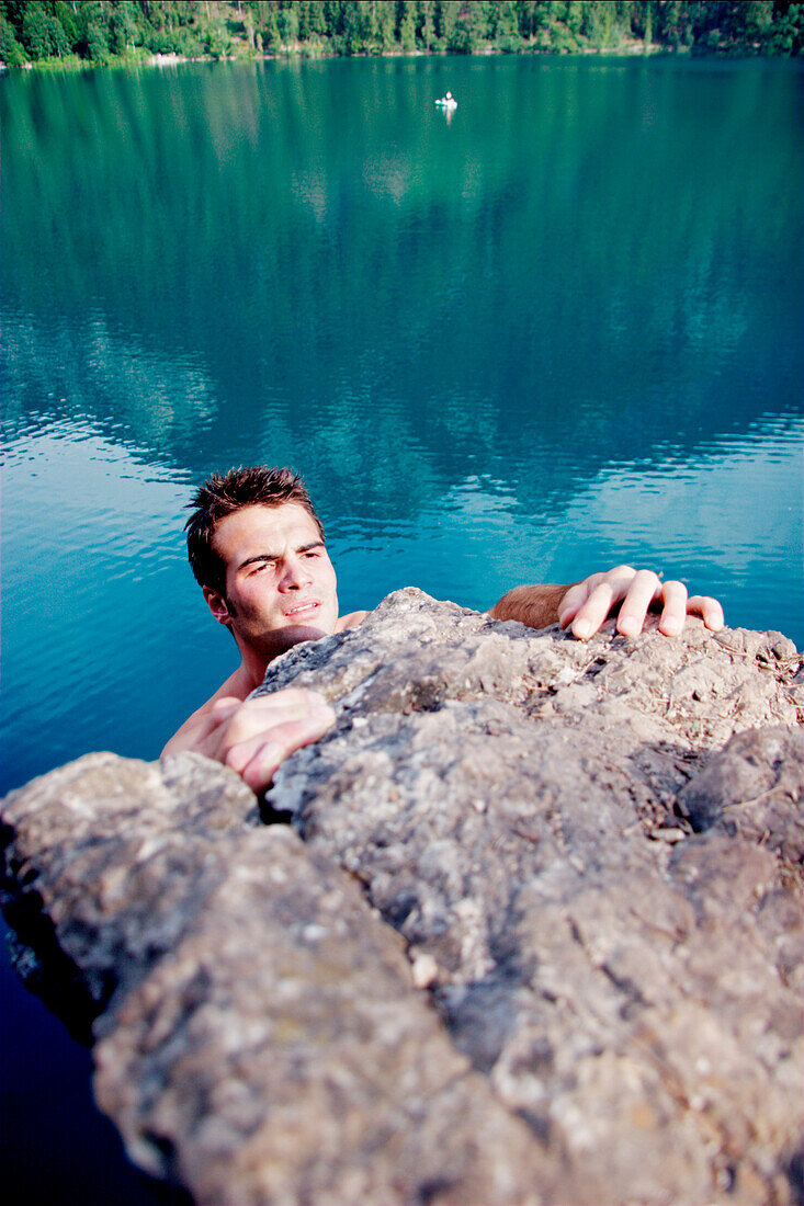 Young man climbing, Lake Alpsee, Schwangau, Bavaria, Germany