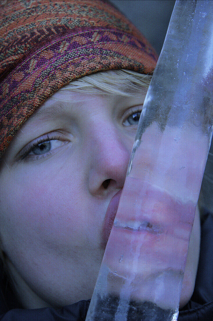 Junge Frau lutscht an einem Eiszapfen, See, Tirol, Österreich