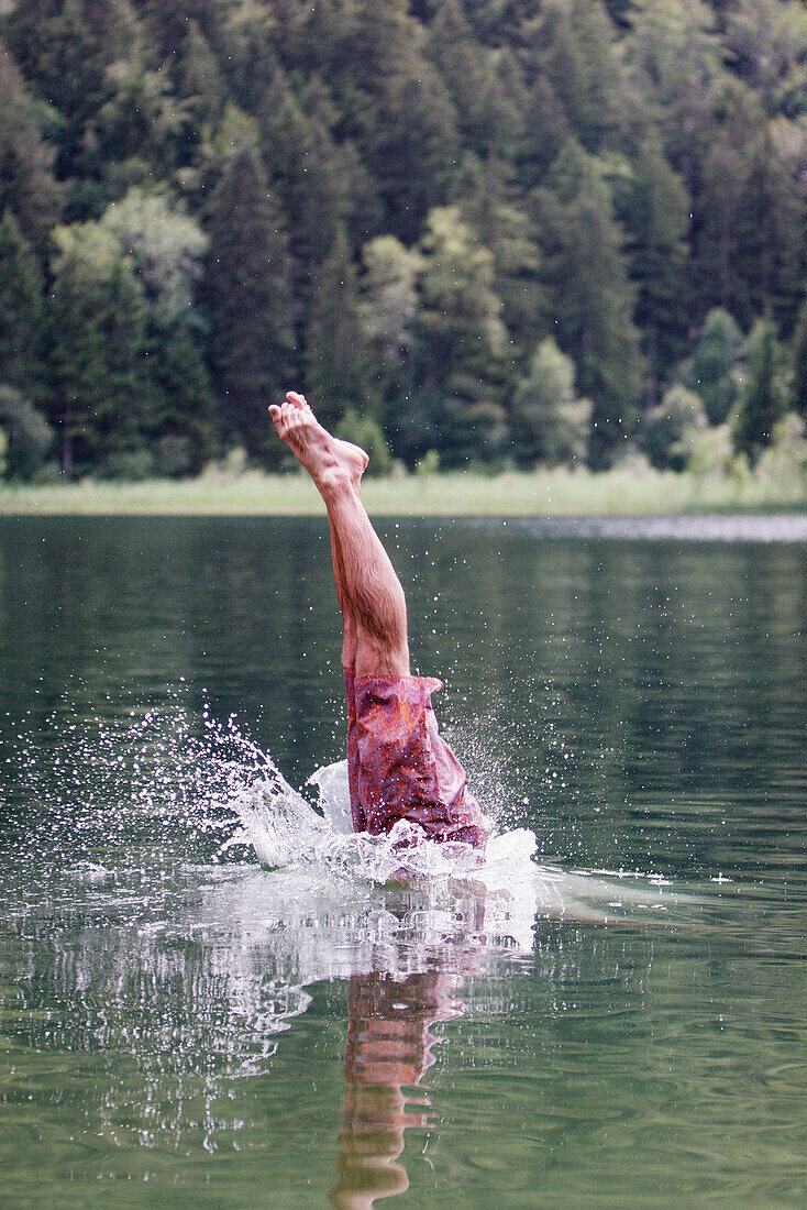 Young man jumping into a lake, Fuessen, Bavaria, Germany