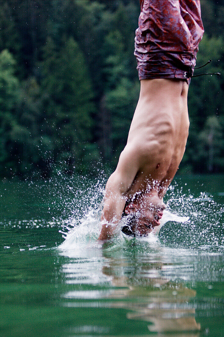 Young man jumping into a lake, Fuessen, Bavaria, Germany