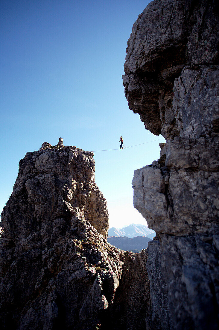 Young man balancing over a rope between to rocks, Oberstdorf, Bavaria, Germany