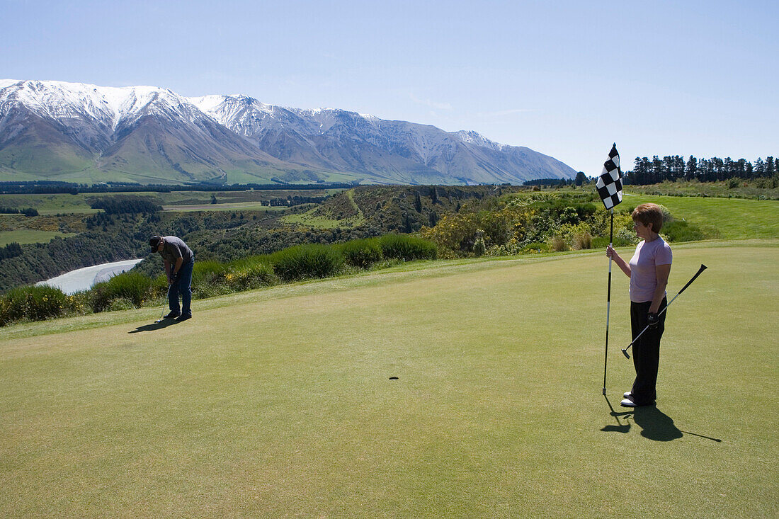 Golfer auf Green von Bahn 16 des Terrace Downs High Country Resort Golfplatz, mit Blick auf die Rakaia Gorge Schlucht, nahe Mount Hutt, Canterbury, Südinsel, Neuseeland