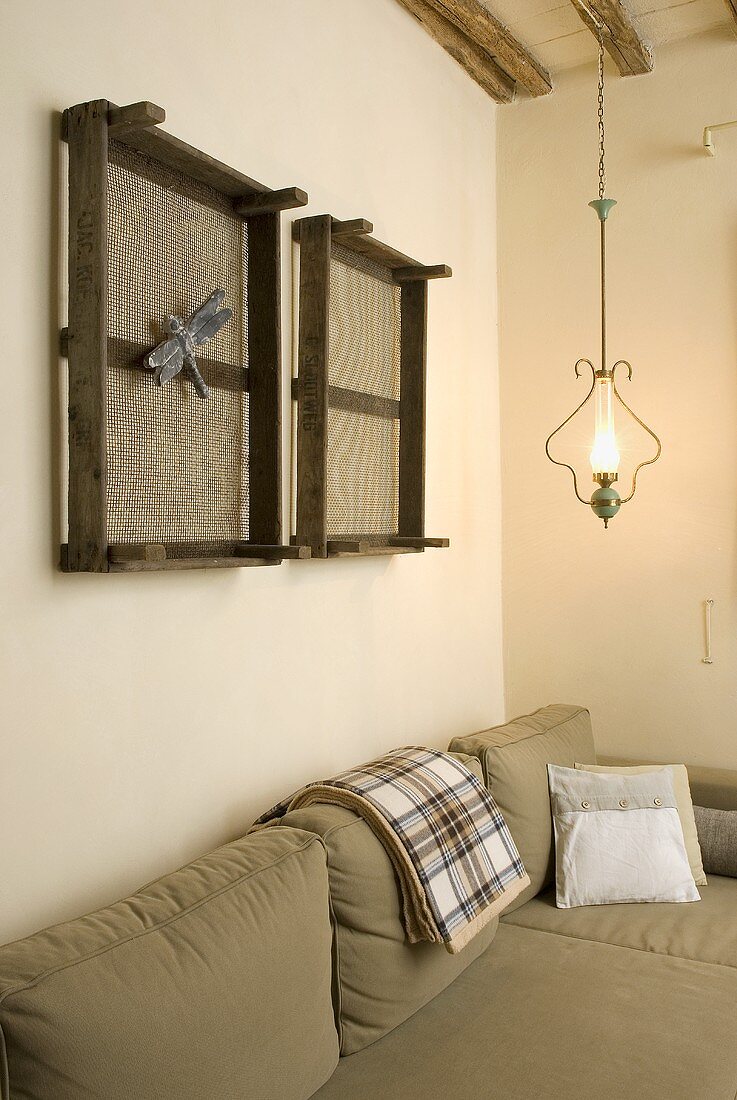 Bright green upholstered sofa with hanging kerosene lamp and old beehive frames on a wall