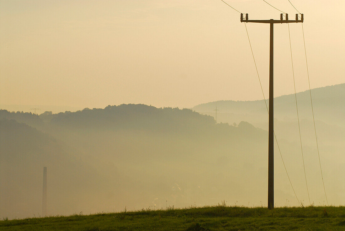 Strommast, Hörselberge im Morgennebel bei Sonnenaufgang, Thüringen, Deutschland