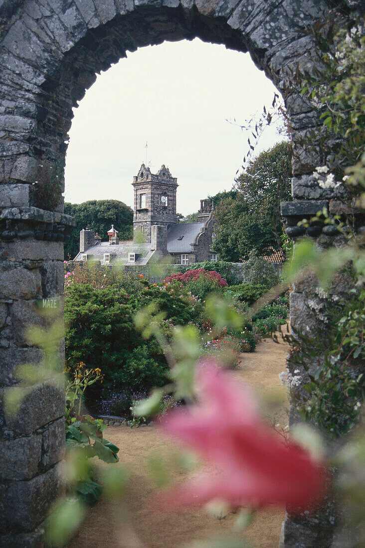 The Seigneurie Garden with view through an arch towards a church, Sark, Channel Islands, Great Britain