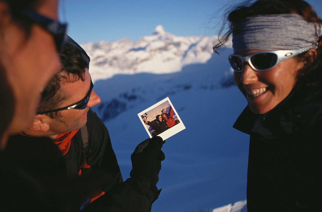 Man showing photograph to two friends, Snowshoeing, Mountain sports, Winter, Nebelhorn, Allgaeu, Bavaria, Germany
