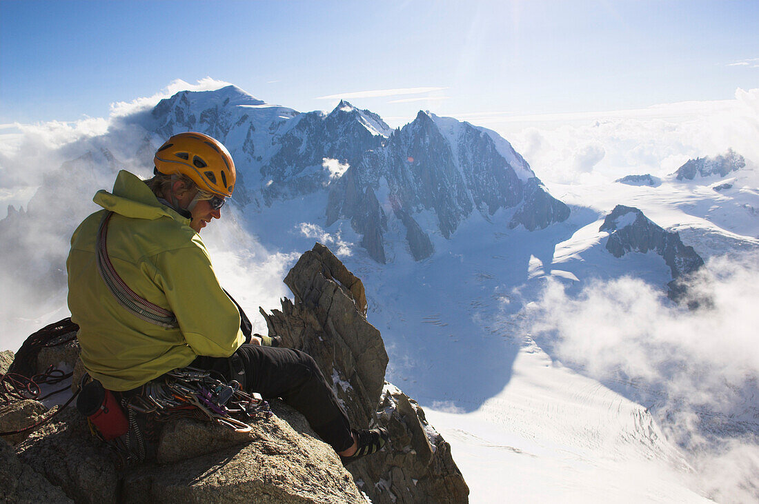 Mountaineer sitting on top of mount Dent du Geant (4012 m), Mont Blanc, France, Italy