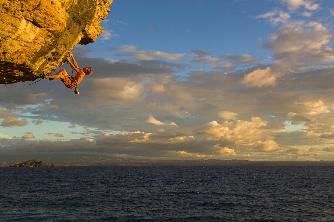 Freeclimber klettert an Felsvorsprung über Meer, Tsaranoro Be, Andringitra Nationalpark, Madagaskar