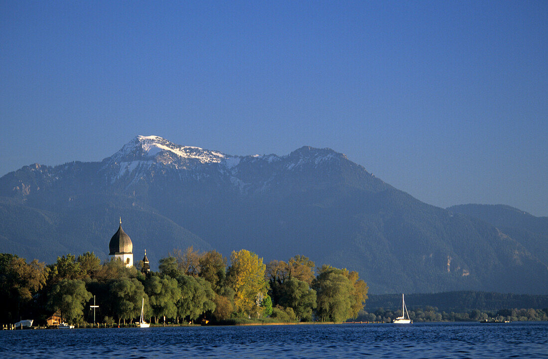 Island of Frauenchiemsee with church tower and view to snow covered Hochgern, lake Chiemsee, Upper Bavaria, Bavaria, Germany