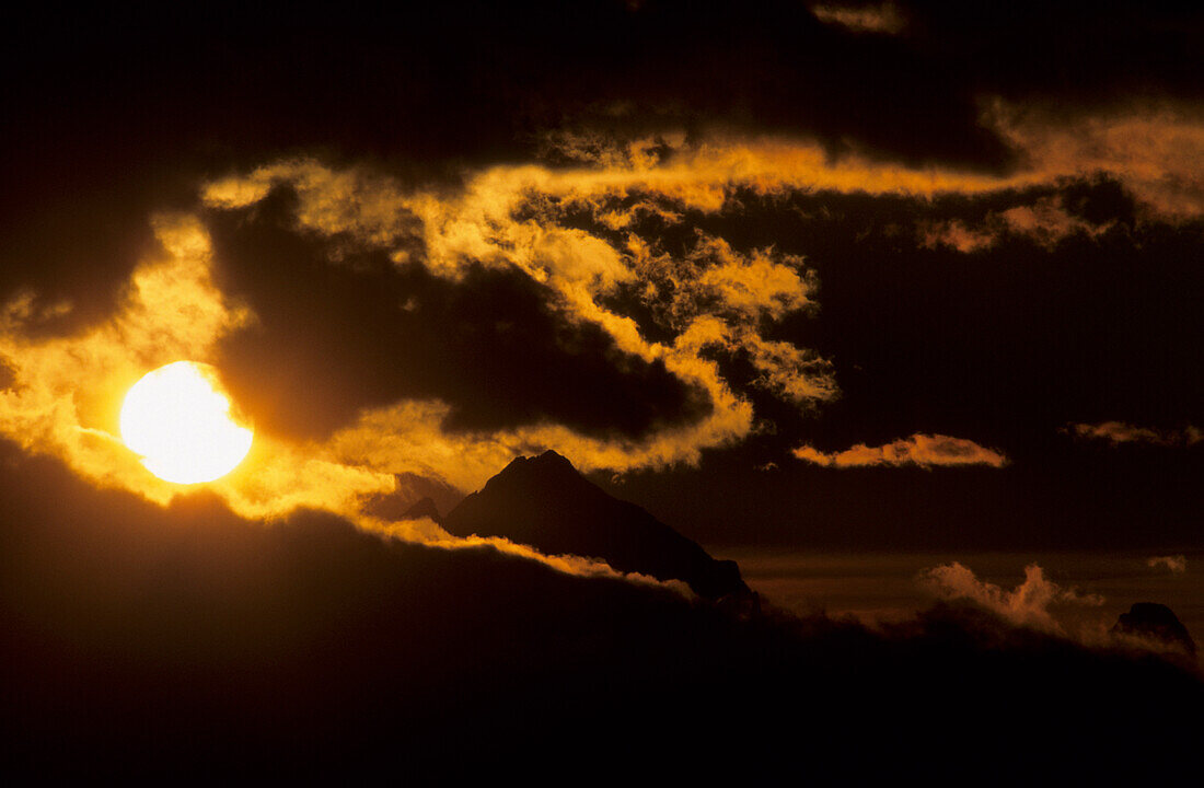 big sun with silhouette of Antelao and dramatic clouds, Dolomites, Venezia, Italy