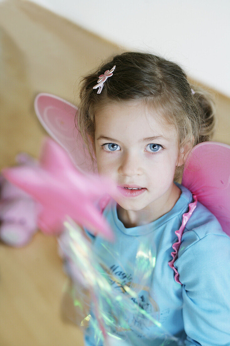 Mädchen (3-4 Jahre) mit Schmetterlingsflügeln und Zauberstab