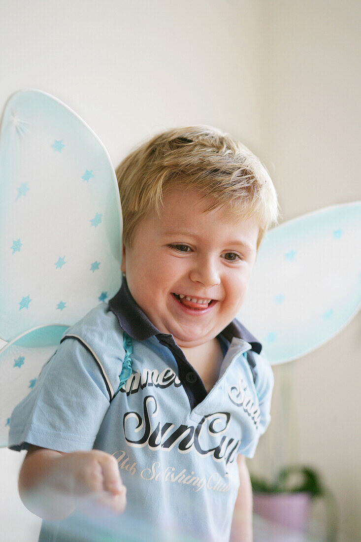 Giggling boy (3-4 years) wearing butterfly wings