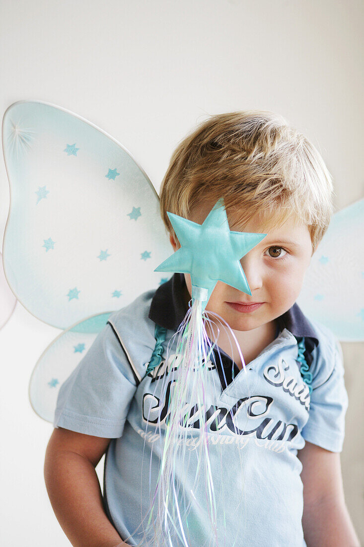 Boy (3-4 years) wearing butterfly wings holding wand