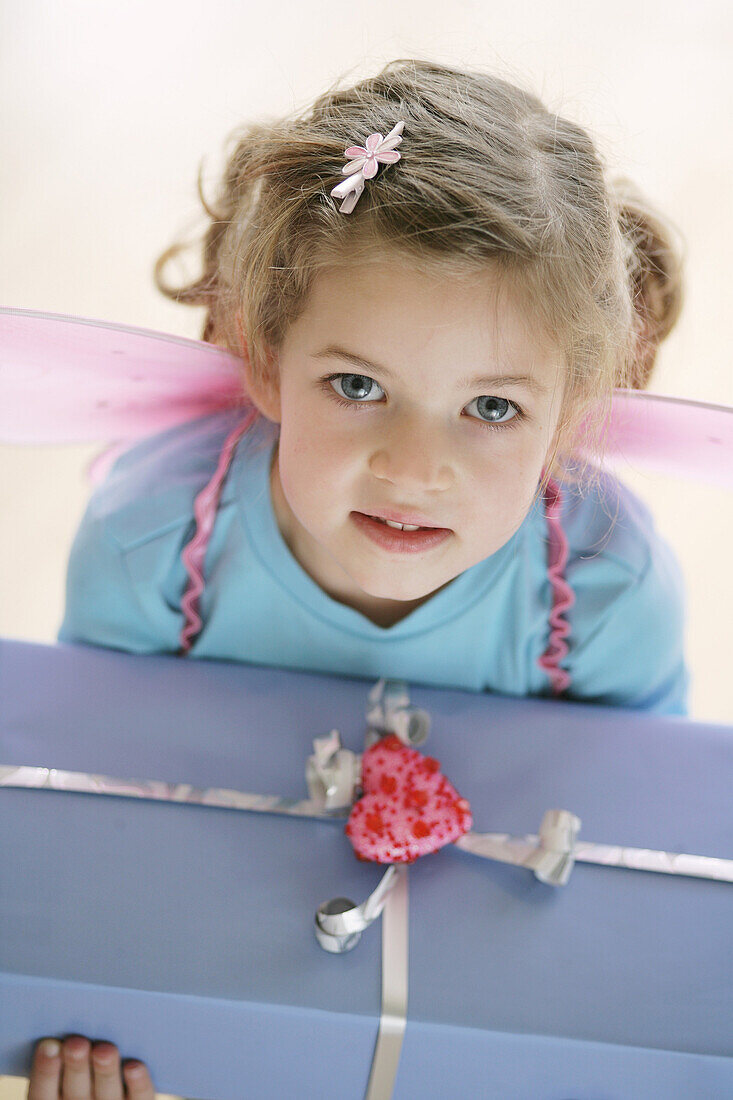 Girl (3-4 years) wearing butterfly wings holding a present
