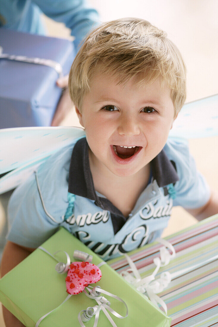 Junge (3-4 Jahre) mit Schmetterlingsflügel trägt Geschenke